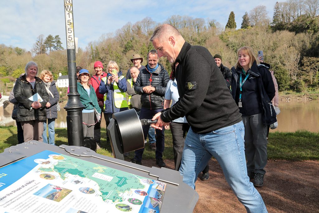 Iolo Williams yn arddangos y bocs sŵn newydd ar Lwybr Arfordir Cymru ger glan yr afon yng Nghas-gwent 