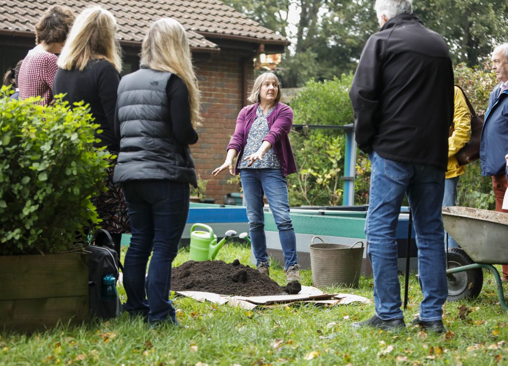 A woman instructs a group of people about no-dig gardening