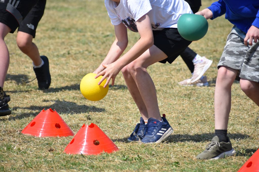 Children playing. Children placing a ball on a sports cone