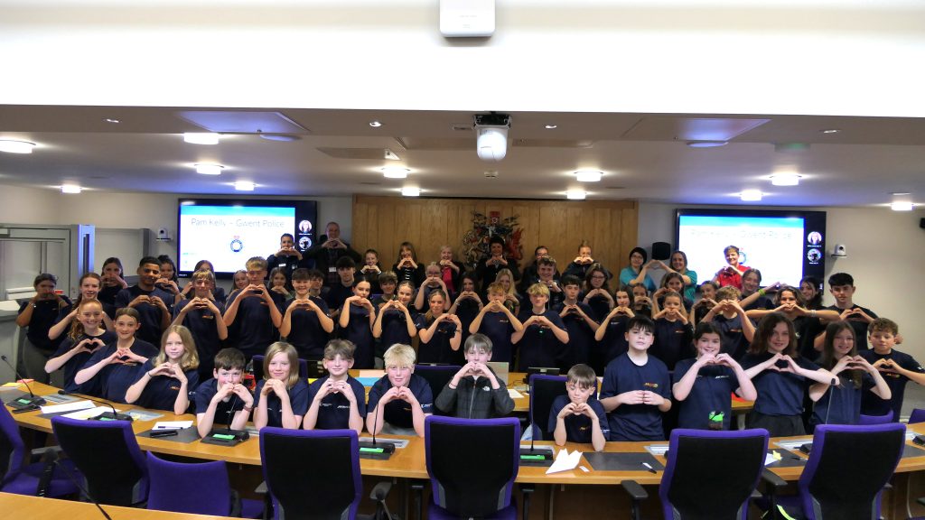 Group of people holding their hands in a heart shape.